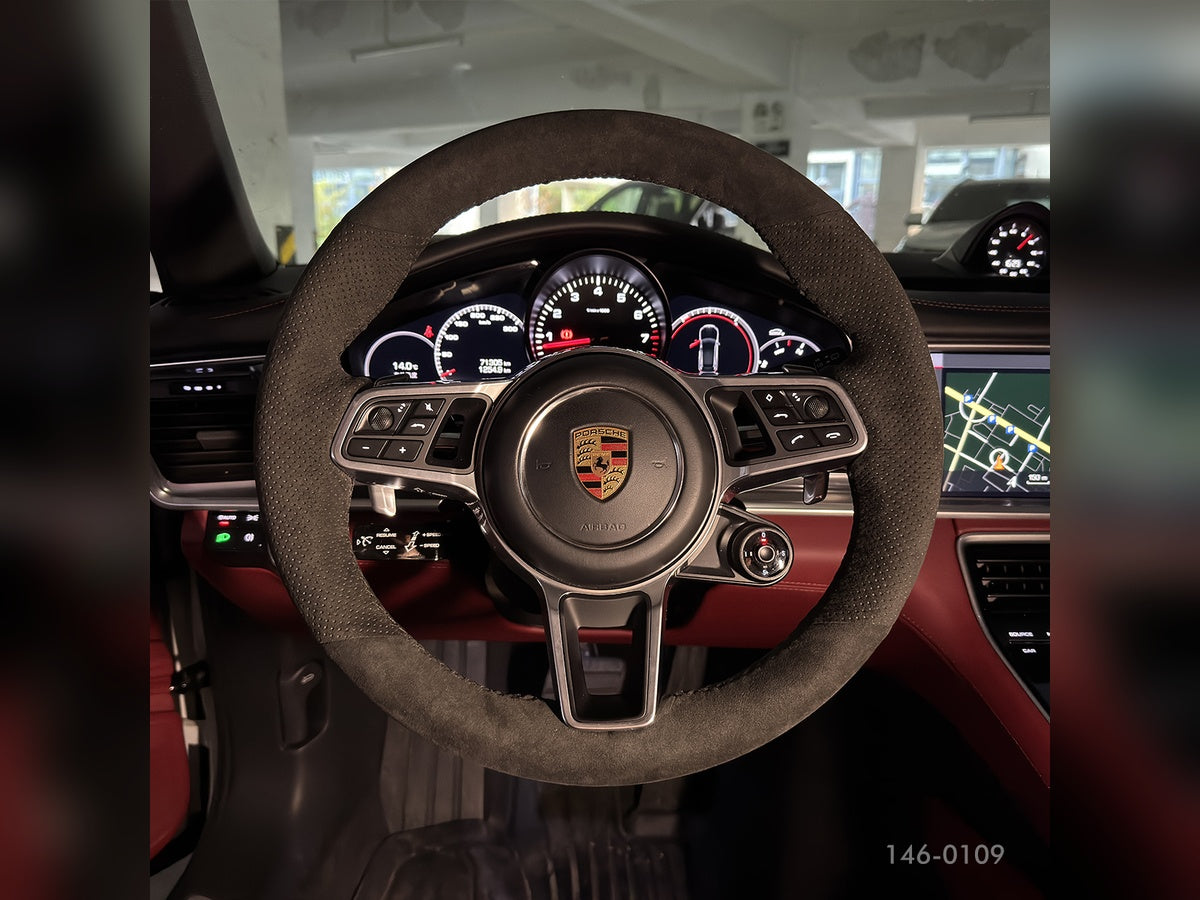 Porsche-Lenkrad mit dunklem Bezug und perforierten Griffbereichen