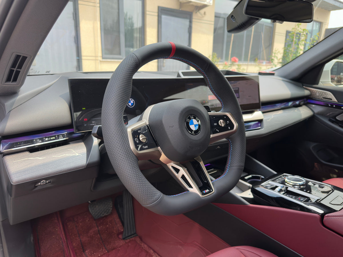 Bezogener BMW-Lenkradkranz im Innenraum mit roten Sitzen